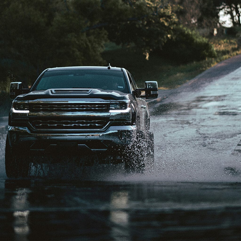 lifted truck driving through flooded road